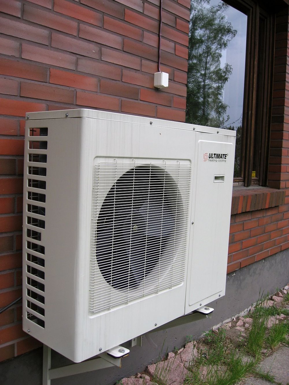 An air source heat pump on the side of the side of a brick wall.